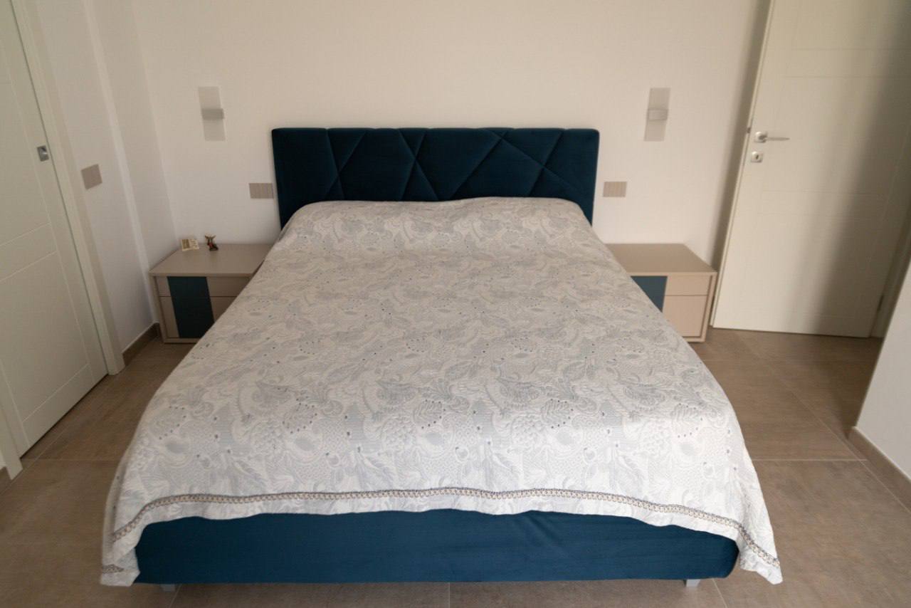 Camera da letto con letto imbottito blu e comodini bicolore