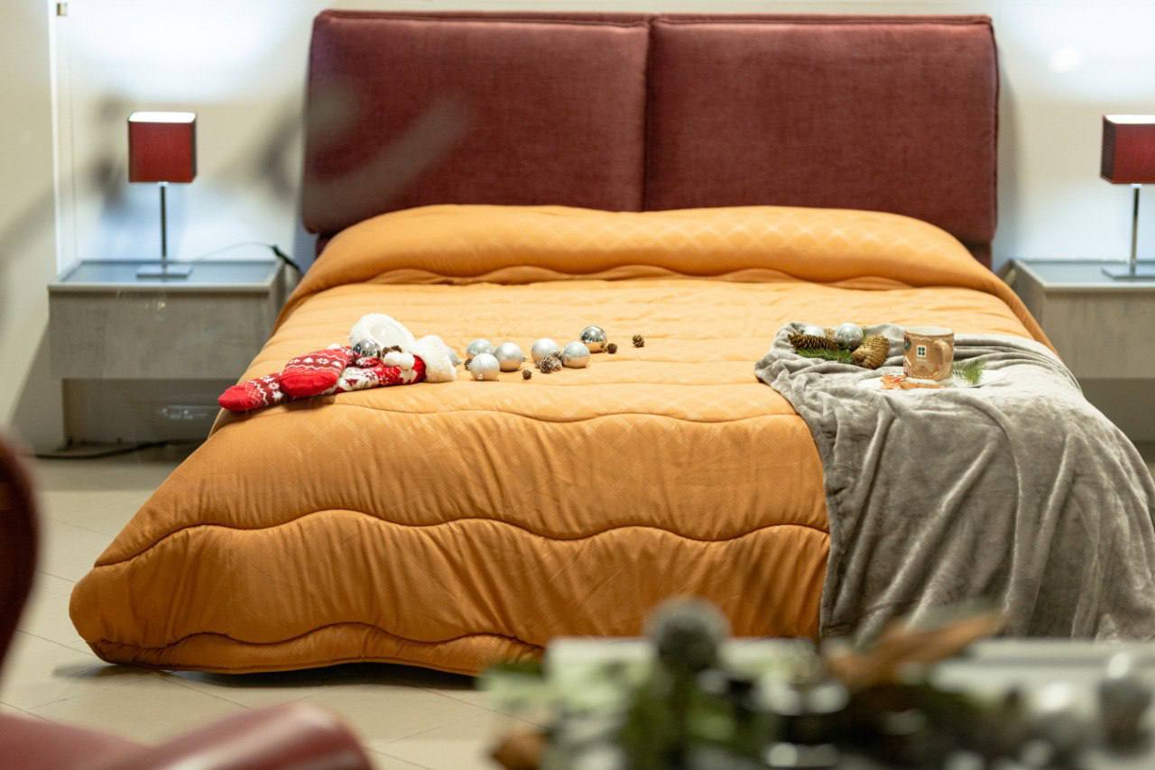 Letto matrimoniale con testiera imbottita bordeaux e lampade coordinate